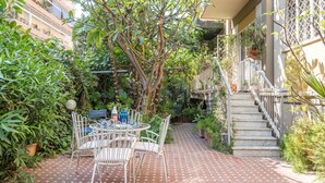 Eine Terrasse mit Fliesenboden, einem runden Tisch mit Stühlen und einer Treppe zu einer oberen Ebene.