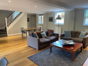 A spacious living room with a wooden floor, two sofas, a coffee table, and a dining area with a table and chairs.