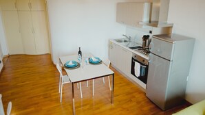 Eine kleine Küche mit Esstisch, Stühlen, Spüle, Herd und Kühlschrank.