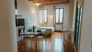 Ein kleines Zimmer mit Küchenzeile, einem Bett und einem kleinen Tisch mit Stühlen.