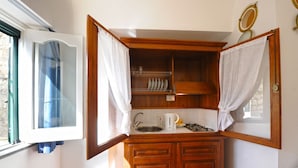 A compact kitchen with wooden cabinets, a sink, and a kettle. - White Daisy is a small villa on two floors (Praiano)