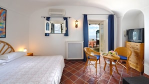 A bedroom with a bed, a table with chairs, a dresser, a television, and a view of the outside. - White Daisy is a small villa on two floors (Praiano)