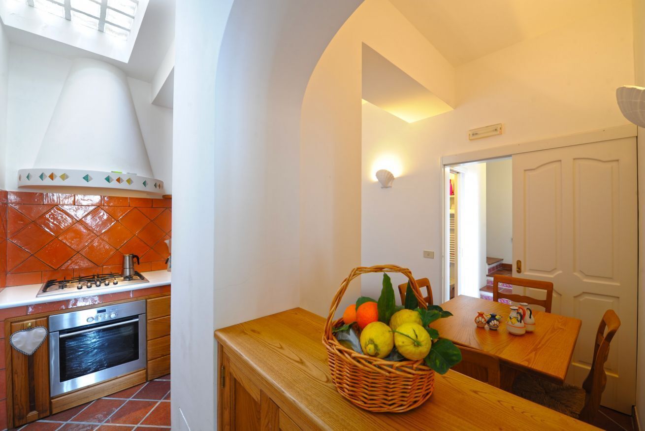 Una cocina con estufa, horno y comedor con mesa y sillas.