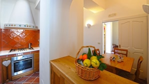 A kitchen with a stove, oven, and a dining area with a table and chairs. - White Daisy is a small villa on two floors (Praiano)