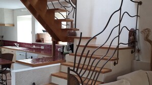 A modern interior with a wooden staircase, a kitchen area, and a living space with a sofa and decorative items. - mansion - 3 rooms - 6 persons (Taulé)
