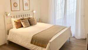 A neatly made bed with a white headboard, two framed pictures on the wall, and a window with sheer curtains. - Fantastic apartment with a wonderful panoramic view of Lake Como  (Dorio)