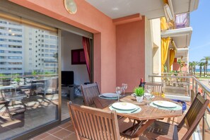 Ein Balkon mit Tisch für zwei Personen, Stühlen und einem Blumentopf.