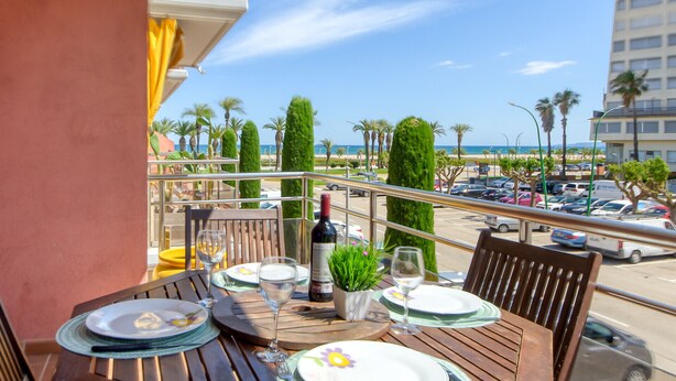 Ein Balkon mit Esstisch, der auf einen Parkplatz und einen Strand blickt.