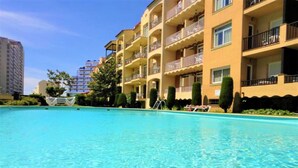 Ein klares, blaues Schwimmbecken, umgeben von einem mehrstöckigen Gebäude mit Balkonen.