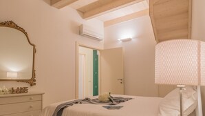 A bedroom with a bed, a dresser, a mirror, and an air conditioning unit.
