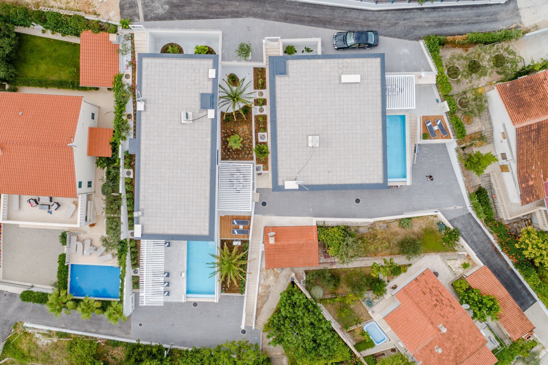 An aerial view of a residential area with two large buildings, a swimming pool, and a small garden area.