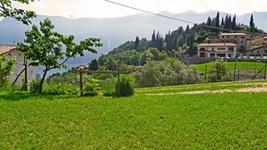 A rural landscape with a view of mountains, a lake, and a few buildings.