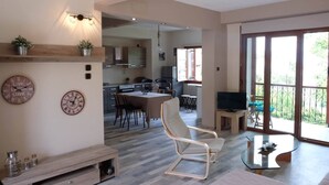 A spacious living area with a dining table, a TV, and a balcony with a railing. - VILLA SOFIA (ground floor self - contained apartment) (Marathos)