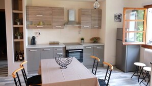 A modern kitchen with a dining area, featuring a central island, built-in cabinets, and a window with a view. - VILLA SOFIA (ground floor self - contained apartment) (Marathos)