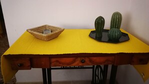 A small table with a yellow tablecloth, a woven basket, and three cacti.