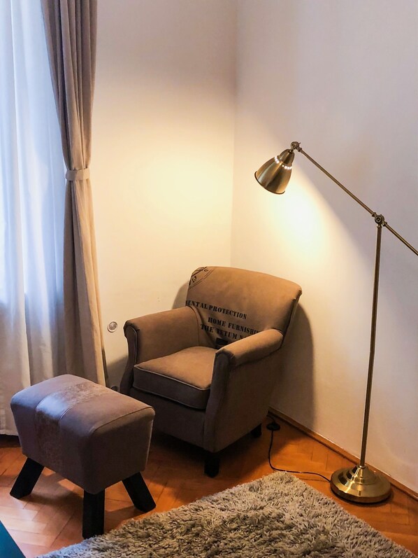 Une pièce comprenant un fauteuil marron, un petit pouf, une lampe sur pied et un tapis.
