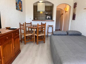 Una camera compatta con tavolo da pranzo, sedie, un letto, angolo cottura e un piccolo armadietto.
