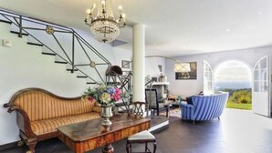 A spacious living area with a staircase, a chandelier, a sofa, and a view of the outdoors. - Elegant Villa near Lucca with big and panoramic garden and private pool (Capannori)