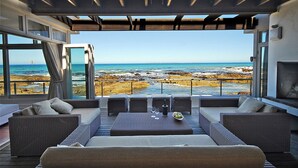 Een modern terras buiten met uitzicht op de oceaan en een rotsachtige kustlijn.