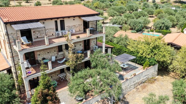 A multi-story building with balconies, outdoor seating, and a swimming pool. - Pool, beach and relax! 4 pax (Gioiosa Marea)