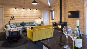 Interior acogedor de una cabaña con sofá, sillón amarillo y chimenea.