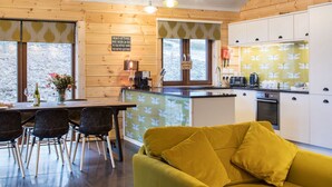 Una cocina acogedora con paredes de madera, una zona de comedor con sillas y un sofá amarillo.