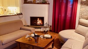 Un salon avec une cheminée, deux canapés, une table basse et, au fond, un coin cuisine.