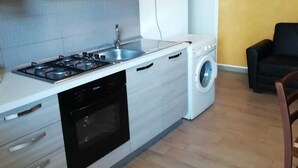 A compact kitchen with a gas stove, sink, dishwasher, and a washing machine. - Villa Barletta apartment in villa ground floor n.2 (Marina di Acate)