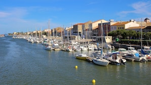 A marina with boats docked along a waterfront, surrounded by buildings with varied architecture. - Gites de France Blue by the sea. Free WIFI. (Port-La-Nouvelle)