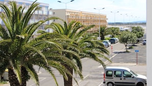 A parking lot with palm trees, a white van, and a building with multiple floors in the background. - Gites de France Blue by the sea. Free WIFI. (Port-La-Nouvelle)