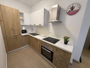 A modern kitchen with wooden cabinets, a stainless steel sink, a microwave, and an oven.
