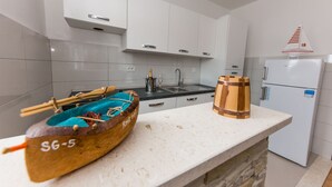 A kitchen with white cabinets, a sink, a wooden barrel, and a sailboat model.