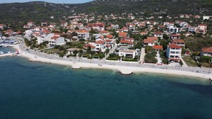 An aerial view of a coastal residential area with houses, a beach, and a marina.