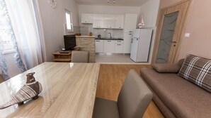 A compact living space with a dining area, a sofa, a kitchen, and a small table.