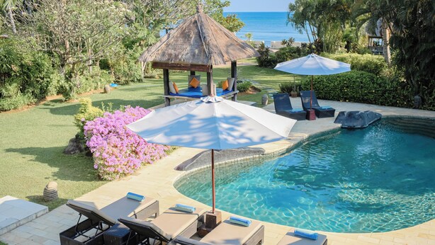 A pool area with lounge chairs, a gazebo, and a view of the ocean. - Fabulous villa right on the beach with large pool, tropical garden & staff (Dencarik/Lovina)