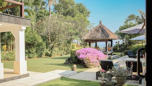 A well-maintained garden with a gazebo, outdoor seating, and a pool area. - Fabulous villa right on the beach with large pool, tropical garden & staff (Dencarik/Lovina)