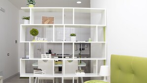Een moderne woonkamer met een wit wandrek, een groene bank en een keuken in de achtergrond.