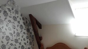 Un dormitorio con cabecera de madera, cama con ropa de cama blanca y cortina estampada.