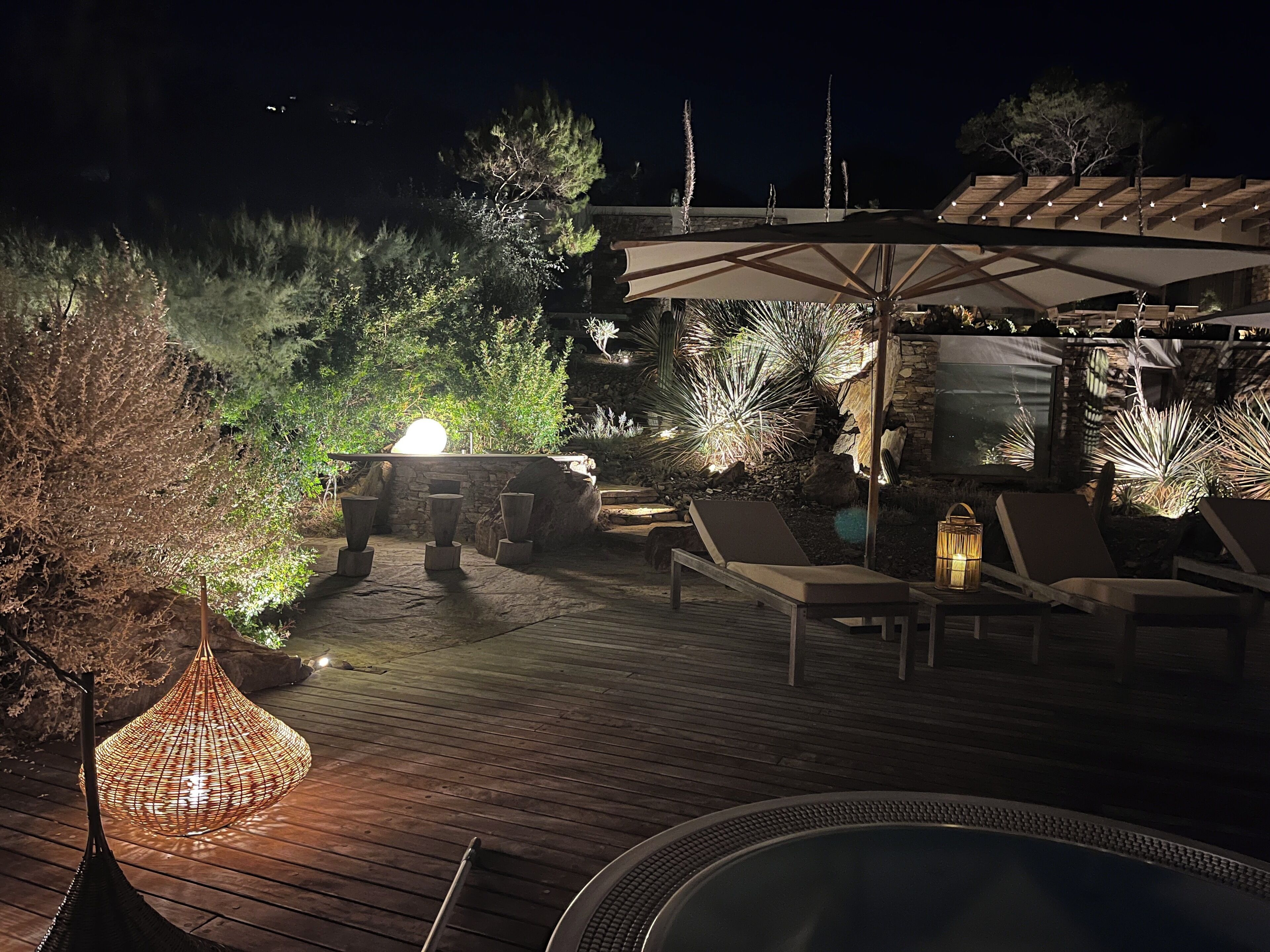A wooden deck with lounge chairs and a hot tub.