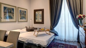A hotel room with a bed, a bedside table, a chair, a small table with a tray of fruit and two cups, a mirror, and curtains. - Rome Boutique Apartments, seductive, close on foot to the vatican and the center (6900334)