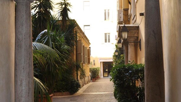 A cobblestone alleyway framed by classical columns, leading to a building entrance. - Rome Boutique Apartments, seductive, close on foot to the vatican and the center (6900334)