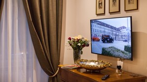 A hotel room with a television displaying a cityscape, a vase with flowers, and a decorative bowl on the dresser. - Rome Boutique Apartments, seductive, close on foot to the vatican and the center (6900334)