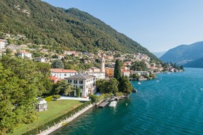A lakeside town with buildings along the water, a prominent tower, and lush greenery. - Regina Villetta, Laglio, Italy (Laglio)