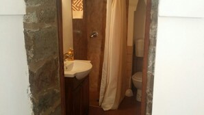 A small bathroom with a sink, toilet, and shower curtain. - In Kasuzza. (Pantelleria) (Pantelleria)