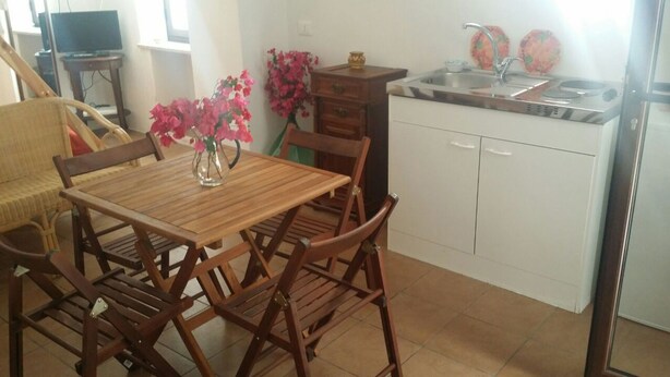 A small kitchen with a dining table and chairs, a sink, and a stove. - In Kasuzza. (Pantelleria) (Pantelleria)