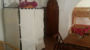 A room with a wooden table, chairs, a white curtain, and a wooden door. - In Kasuzza. (Pantelleria) (Pantelleria)