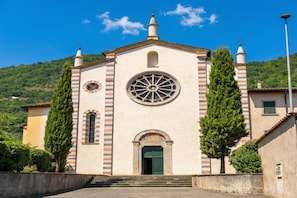 Una iglesia con un ventanal circular central, una torre del campanario y una escalera que conduce a la entrada.
