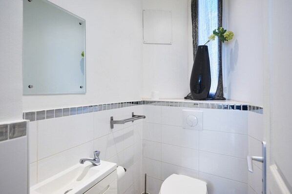 Une salle de bain moderne avec un lavabo blanc, un miroir et des toilettes.