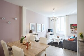 A modern living room with a dining area, a TV, and artwork on the walls.