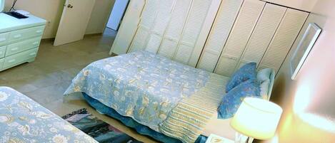 A bedroom with two beds, a television, a desk, and a wardrobe.